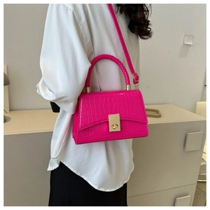 Detail of fuchsia crocodile texture handbag with gold-tone hardware and woven handle