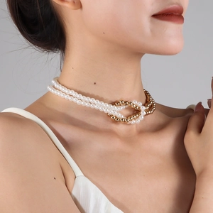 Close-up of double-layer choker with white pearls and gold bead knot on neck