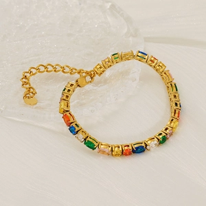 Bracelet tennis plaqué or avec zircons multicolores posé sur de la soie blanche élégante