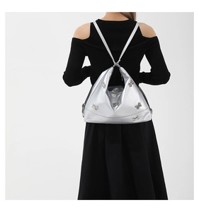 Silver PU hobo bag with metallic butterfly accents worn by a model in a black dress