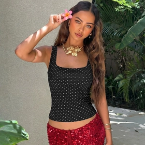 Dettaglio del crop top da donna con scollo a U e motivo a pois in un giardino tropicale