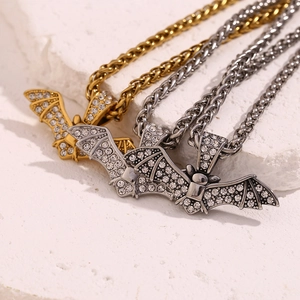 Gros plan de pendentifs chauve-souris hip-hop en or et argent avec strass sur pierre