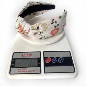 Lightweight floral print cotton knot headband in beige shown on a white digital scale