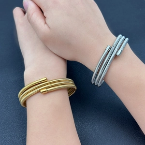 Minimalist spiral spring wire bangles in 18K gold and silver finish on a blue leather base