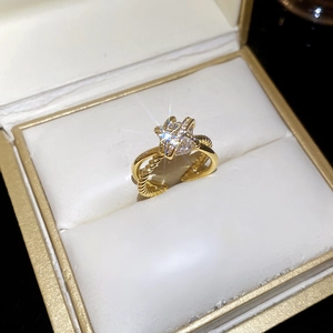 Detail of gold zircon cross ring with star setting and twisted band in jewelry box