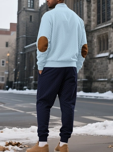 Detail view of men's turtleneck knit sweater with brown elbow patches and navy pants