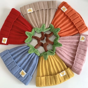 Set of colorful baby pumpkin knit hats with palm tree accents on a white background