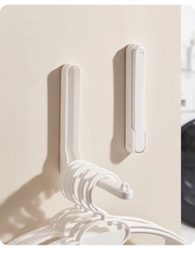 Space-saving wall-mounted folding clothes hanger rack in minimalist white plastic