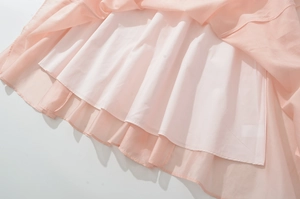 Detailed close-up of pink layered dress hem with white lining and fine stitching