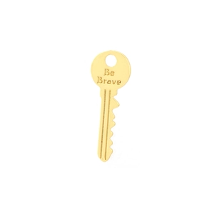 Detailed close-up of a gold-plated key pendant engraved with Be Brave lettering