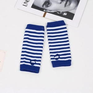 Detailed view of blue and white striped knitted arm warmers with thumb holes on desk