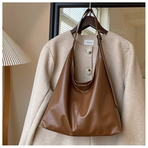 Detailed close-up of a large brown PU leather tote bag with a smooth polished finish