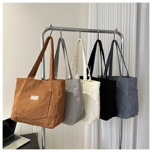 Detailed macro view of corduroy tote bags in five colors hanging on a rack