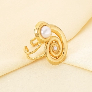 Detailaufnahme des goldenen Spiralrings mit weißen Perlen auf elegantem Seidenhintergrund