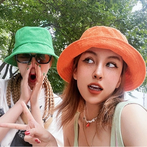 Close-up of bright orange and green terry cloth bucket hats with soft towel texture