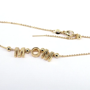Macro shot of gold MOM pendant with S925 certification stamp on a fine bead chain