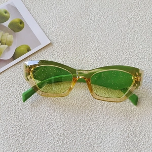 Close-up of green gradient cat-eye sunglasses with glitter lenses on a white background