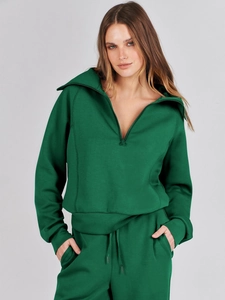 Detail of dark green knit tracksuit featuring half-zip collar and drawstring sweatpants
