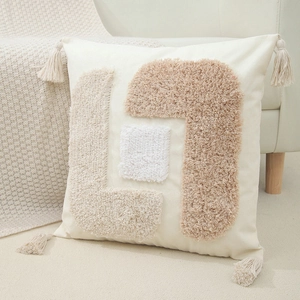Close-up of tufted geometric pattern and decorative corner tassels on cotton linen cushion