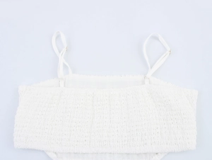 Detailed close-up of white mesh fabric texture and adjustable spaghetti straps on the dress
