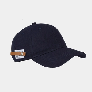Detail view of navy blue baseball cap featuring side leather patch and metal rivet decoration