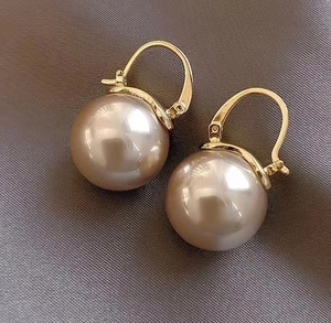 Detailed macro view of champagne pearl earrings with gold metallic finish on leather