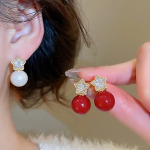 Detail of star-shaped zircon earrings with gold plating and white pearl drop