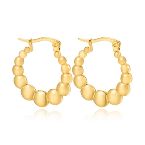 Detail of gold beaded hoop earrings with a polished metallic finish on white background