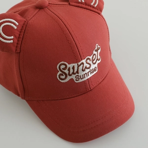 Red kids baseball cap with cute ears and Sunset Sunrise embroidery on a grey background