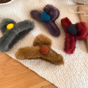Detailed view of four colorful plush hair claws with heart and ball accents on soft fabric