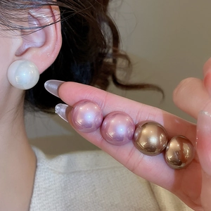 Close-up of large round pearl earrings in white, pink and gold showing high luster
