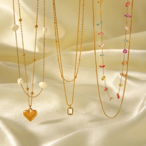 Close-up of triple-layered gold stainless steel necklaces with pearls and gemstones