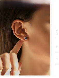 Détail de boucle d'oreille cœur en argent 925 avec pierre bleue portée sur l'oreille