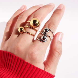 Detailed close-up of golden and silver spiral double-ball rings on a model's hand