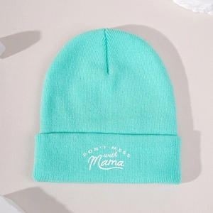 Mint green knit beanie with Don't Mess with Mama embroidery on a beige background