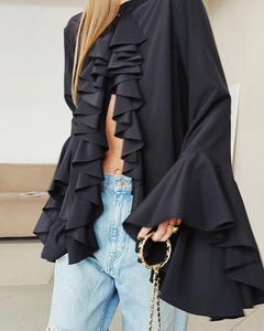 Detail of elegant black ruffled chiffon top with flared sleeves paired with light jeans