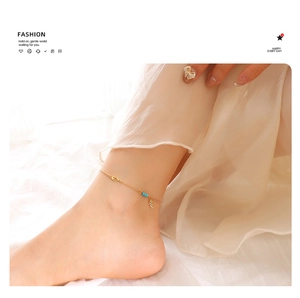 Detail of a gold titanium steel anklet featuring turquoise beads and feather charm on ankle