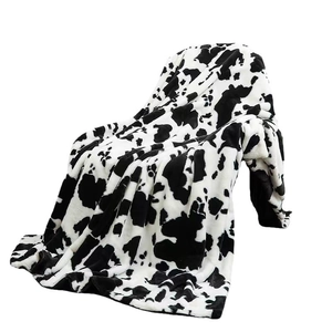 Soft flannel blanket with classic cow print pattern for bed or sofa in black and white