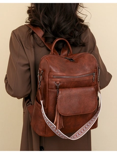 Brown vintage leather backpack detail featuring colorful woven strap and decorative tassel