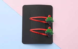 Close-up of red glitter hair clips with festive green resin Christmas tree decorations