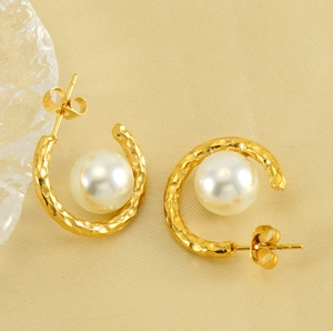Detailed view of C-shaped gold hoop earrings with hammered texture and white pearls