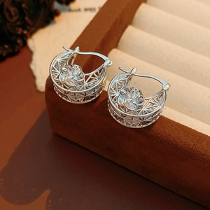 Close-up of silver hollowed flower earrings on a luxury jewelry display box