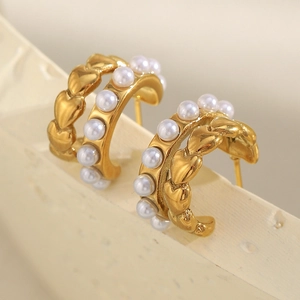 Macro shot of 18K gold plated C-shaped earrings with white pearls and heart reliefs