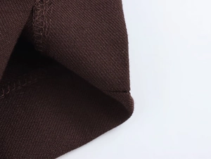 Detailaufnahme von dunkelbraunem Strickstoff mit professioneller Naht und Saumtextur