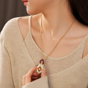 Detail of vintage gold necklace with purple enamel, amber stones and sparkling crystals