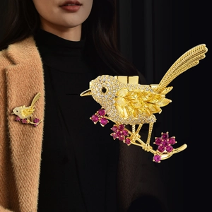 Exquisite gold bird brooch with yellow crystals and purple flowers on camel coat