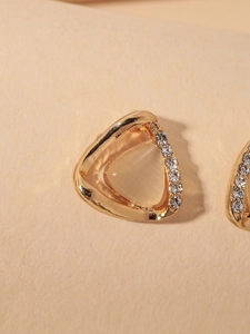 Close-up of golden triangular earrings with cat eye stone and tiny zircon accents