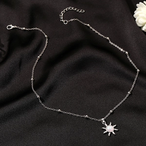 Close-up of opal sun pendant on beaded chain over elegant black silk background