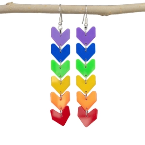 Rainbow acrylic chevron fringe earrings hanging on a branch over a white background