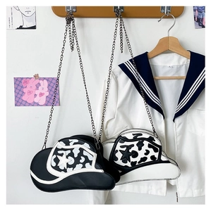 Detail of cowboy hat shaped crossbody bags with cow print and stars on silver chain